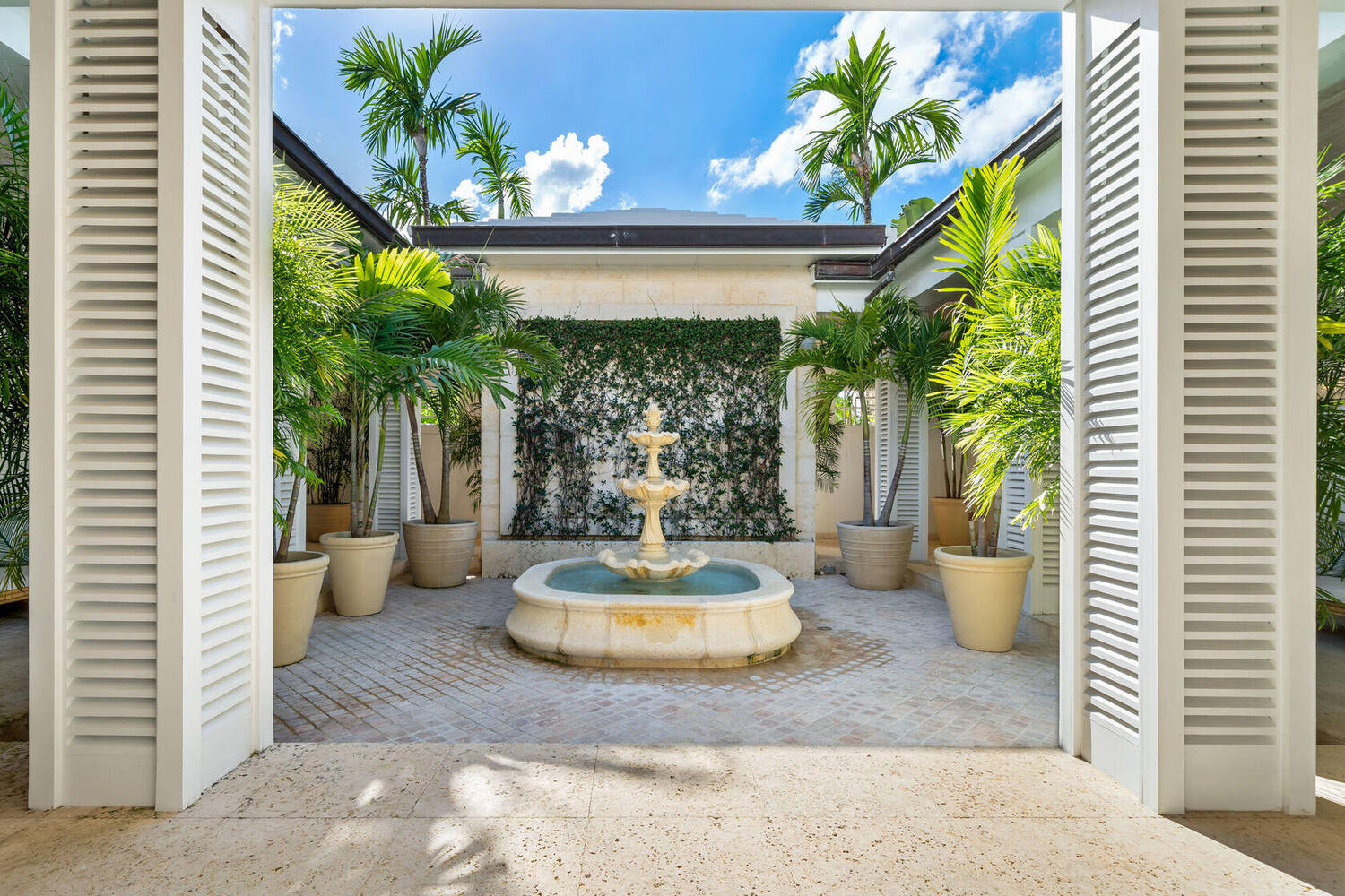 Courtyard fountain framed by shutters and tropical planting